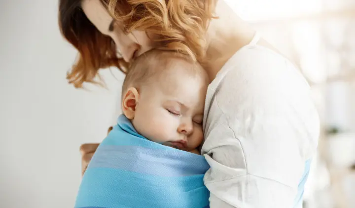 Mutter trägt schlafendes Baby