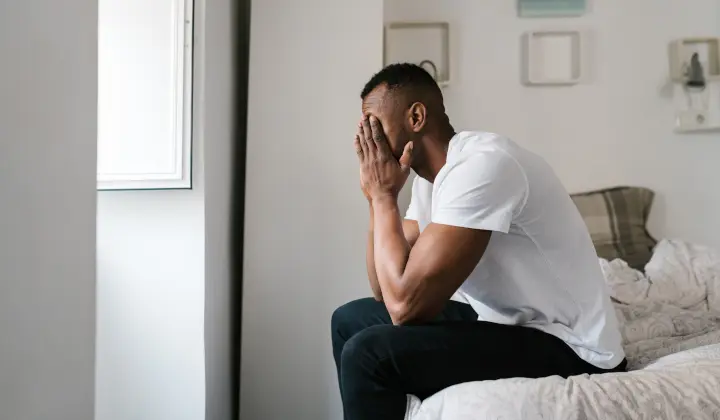 Mann sitzt müde auf Bettkante