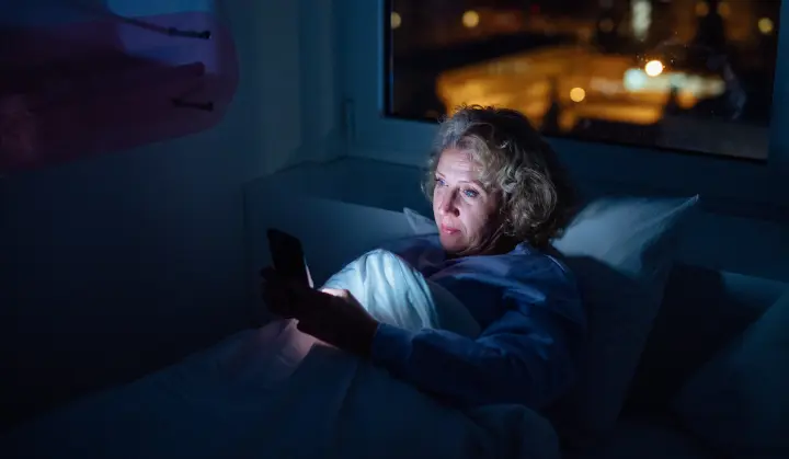 Seniorin im Bett am Smartphone